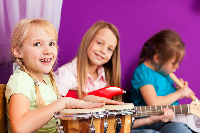 Drei Kinder spielen auf Bongos, Egitarre und Blockflöte