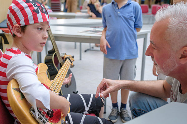 E-Basslehrer Jens Kreft erklärt einem Kind die Bass-Gitarre