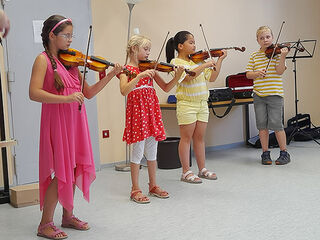 Vier kleine Violinenschüler musizieren gemeinsam